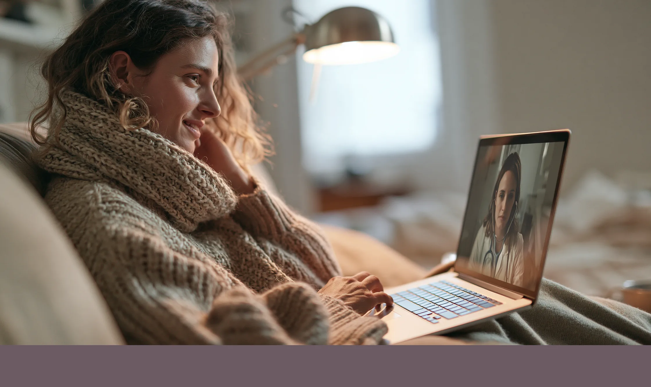 A woman wrapped in a scarf talking with a provider on her laptop