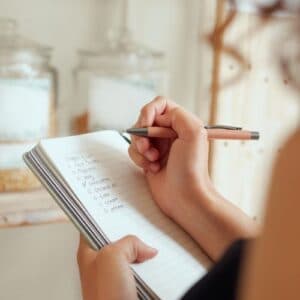 A hand writing a meal plan in a notebook