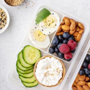 A snack box of cucumber, berries, almonds, egg and cottage cheese