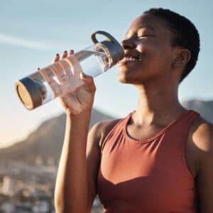 A woman drinking from a water bottle outdoors