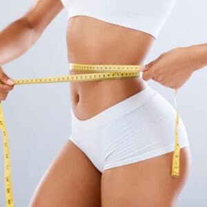 A woman measuring her waist with a tape measure